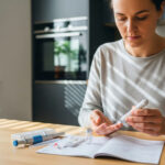 A realistic photo of a person using an at-home health test kit at a kitchen table.