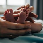 Close-up of newborn's tiny feet held by parent's hands, used to illustrate the importance of checking for birth injury signs.